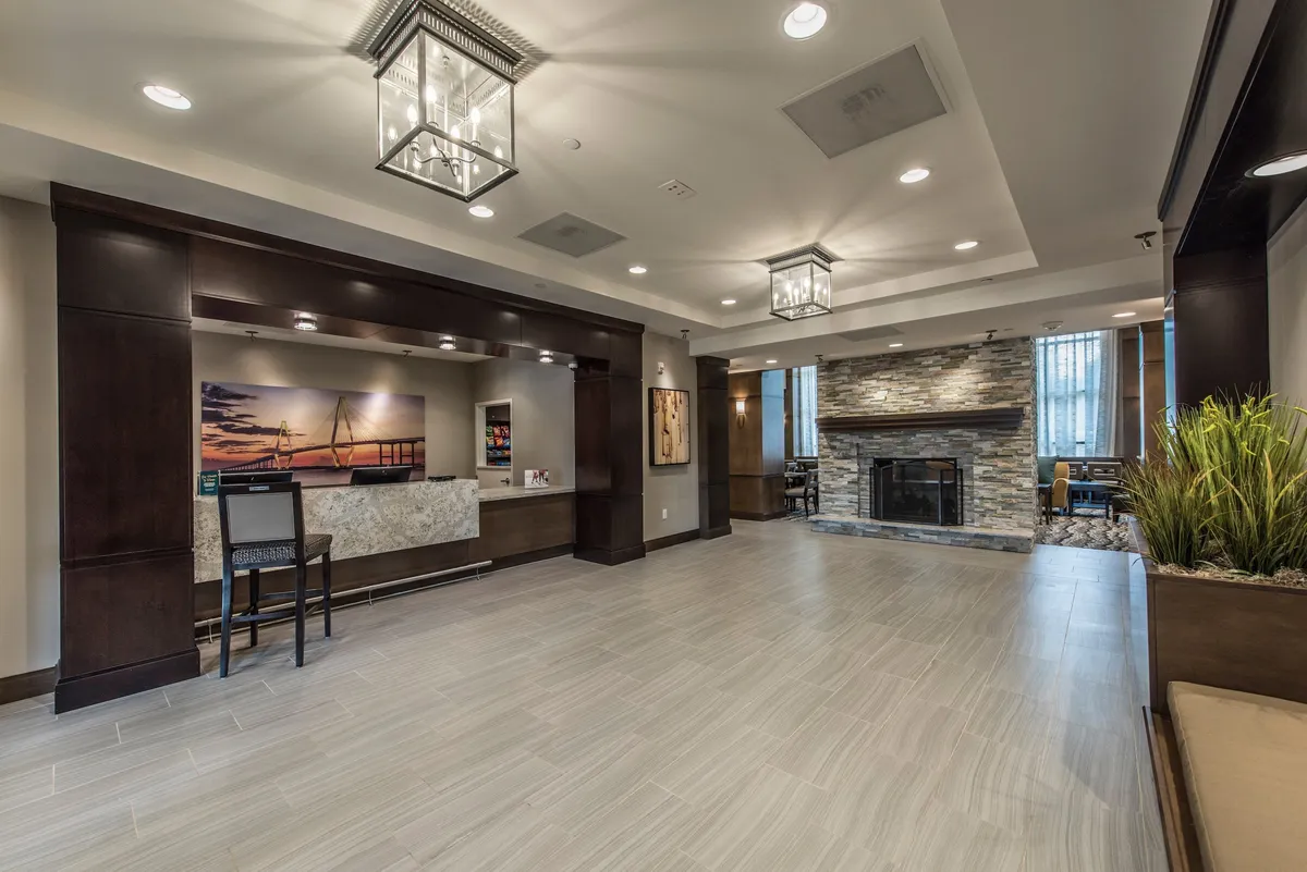 The property’s stylish interior common area features a cozy fireplace, front desk, decorative plants, and artwork. The space exudes warmth and comfort, offering a welcoming environment for guests to gather, relax, or socialize year-round.