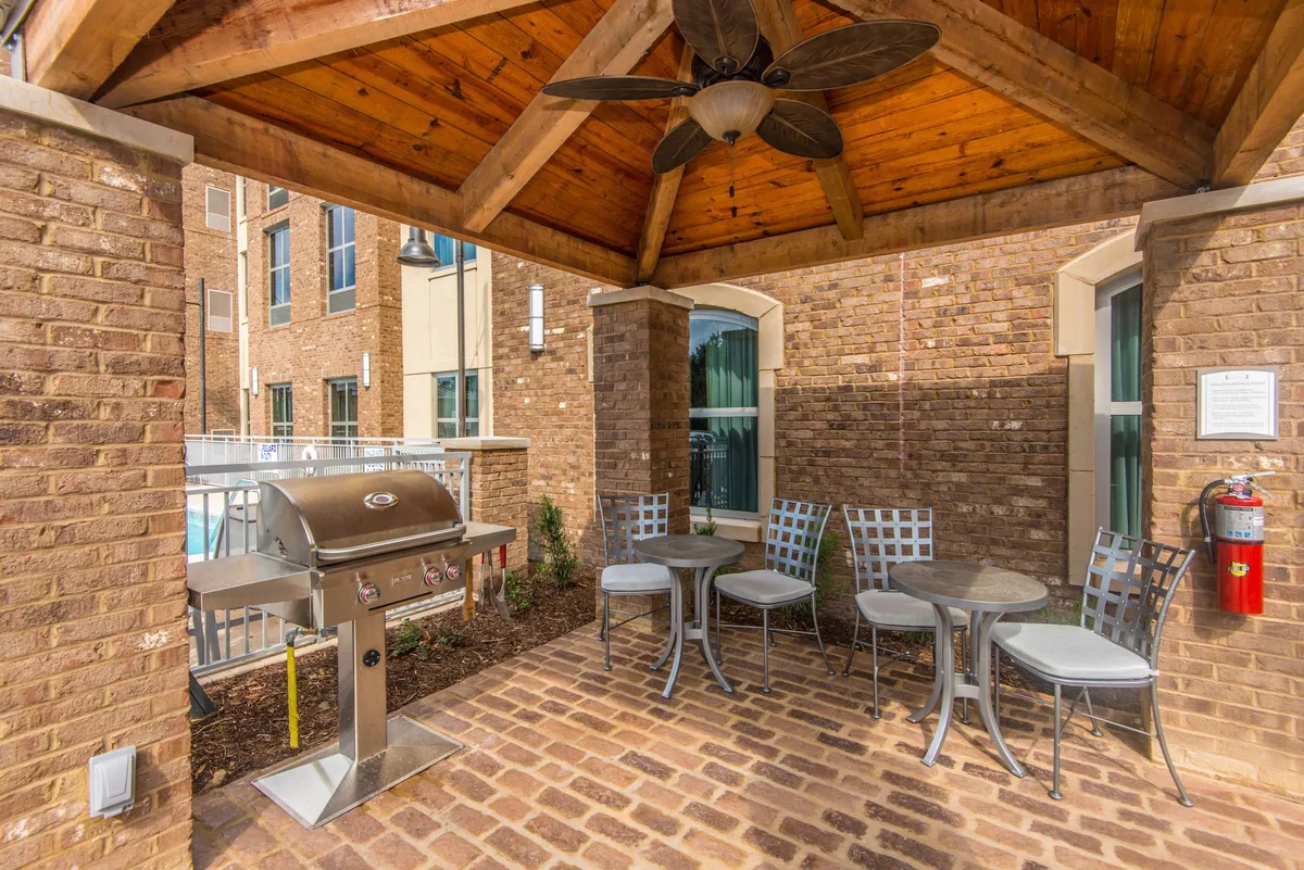This image features an outdoor grill and seating area under a wooden ceiling with brick walls, capturing the casual, communal mood of summer cookouts or family gatherings. The setup suggests easy transitions between fun local activities and relaxed meals back at the property.