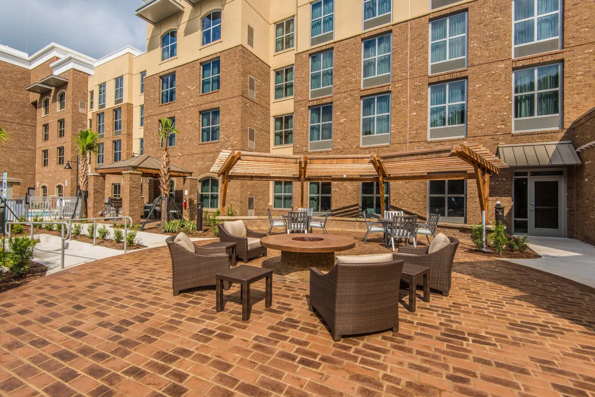 This image captures the exterior of the property, featuring a welcoming fire pit area with a comfortable seating arrangement. The landscaped area and building facade are visible, creating an inviting atmosphere for social gatherings and relaxation after work.