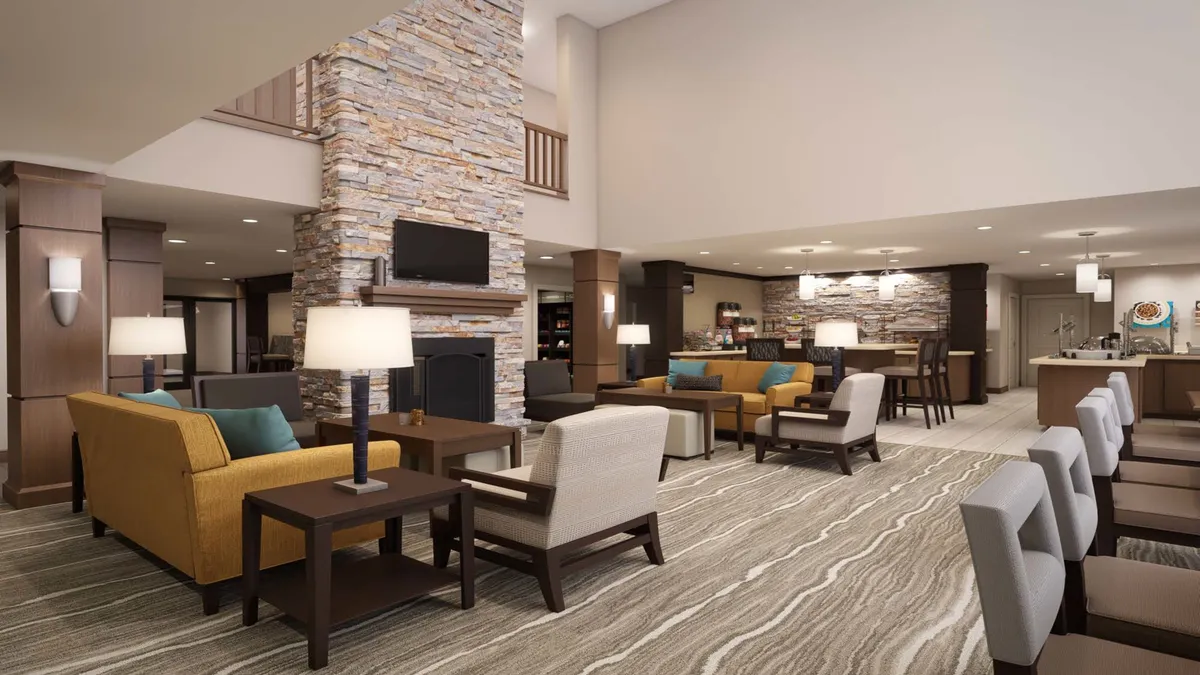 This image shows a cozy interior space featuring a stone fireplace, comfortable seating arrangements, and a modern bar area. The setting encourages guests to gather, socialize, and enjoy both lively conversations and quiet moments.